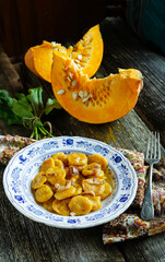 rustic and delicious plate of handmade pumpkin gnocchi topped with crispy greaves, served on an elegant blue and white porcelain dish.