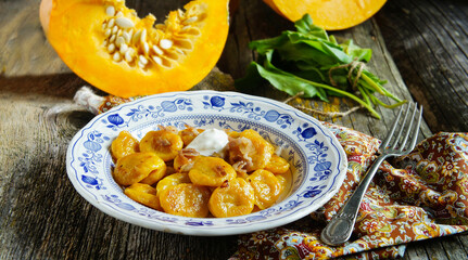 rustic and delicious plate of handmade pumpkin gnocchi topped with crispy greaves, served on an elegant blue and white porcelain dish.