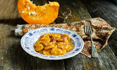 rustic and delicious plate of handmade pumpkin gnocchi topped with crispy greaves, served on an elegant blue and white porcelain dish.