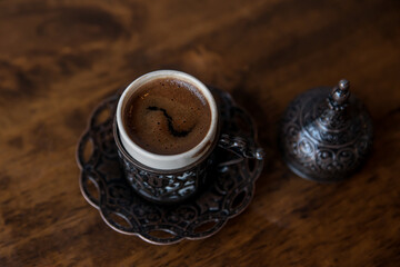 Cup of Turkish coffee in traditional metal cup on old wooden background. Closeup, Selective focus. Top view, flat lay