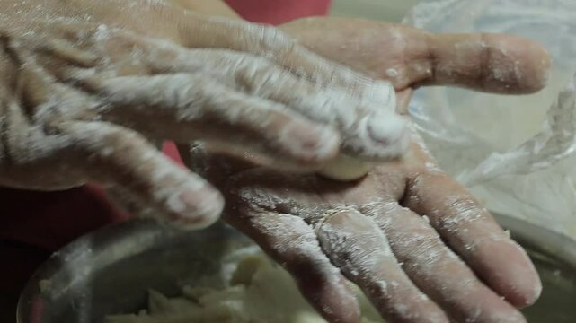
showing a mixture of flour and tapioca sprouts rolled into small balls using hand, manually, the cook
