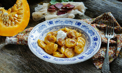 rustic and delicious plate of handmade pumpkin gnocchi topped with crispy greaves, served on an...