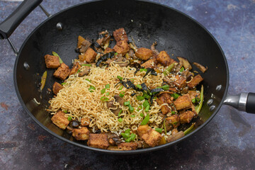Vegan stir fry in wok  consisting of tofu and vegetables, noodles