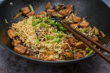 Vegan stir fry in wok  consisting of tofu and vegetables, noodles