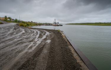 Muddy street view of a barge at port in the Mackenzie River at Inuvik, Northwest Territories, Canada