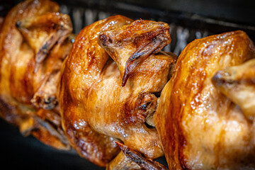 Barbecue roast Chicken in a row turning at industrial roaster grill