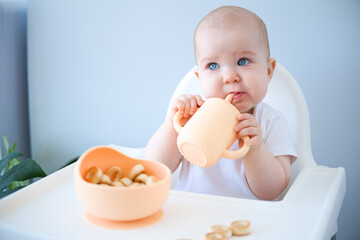 baby sitting in high chair, drinking clean water from baby sippy cup. weaning