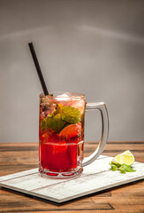 Refreshing Strawberry Mojito soda with Lime and Mint served in mug isolated on wooden table side view of cold beverages drink