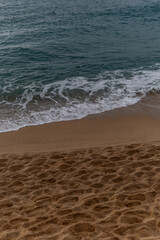 the sea waves at the sandy shore, beating against the rocks. A sailboat at sea. A pigeon sky over a blue sea.