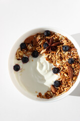 Top View of Bowl of Greek Yoghurt with Freshly Baked Granola, Nuts, Seeds and Blueberries. Healthy Breakfast Food.