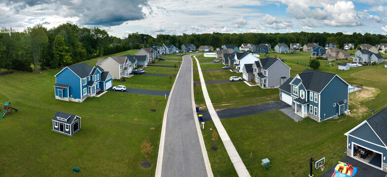 Aerial view of private residential houses in rural suburban sprawl area in Rochester, New York. Upscale suburban homes with large backyards and green grassy lawns in summer season