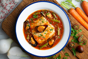 Hake cooked with tomato and mussels. Top view table with  decoration.