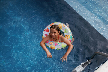 With lifebuoy, learning how to swim. Happy little girl is having fun in the pool