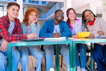 Multiracial group of young students sharing notes and studying in the university library with a laptop