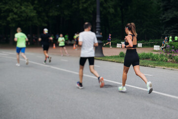 Marathon runners crowd, sportsmen participants start running the half-marathon in the city streets, crowd of sportswomen joggers in motion, group athletes outdoor training competition in a summer day
