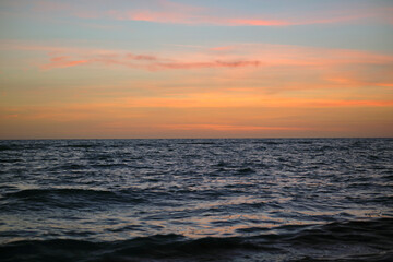 Dramatic red ocean waves at sunset with soft evening sea dark water