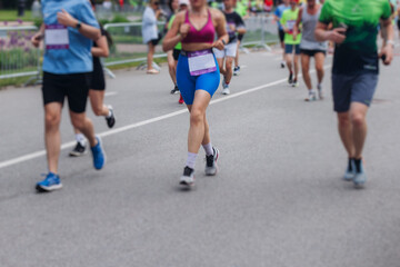 Marathon runners crowd, sportsmen participants start running the half-marathon in the city streets, crowd of sportswomen joggers in motion, group athletes outdoor training competition in a summer day