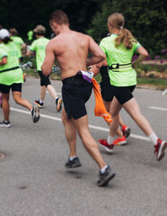 Marathon runners crowd, sportsmen participants start running the half-marathon in the city streets, crowd of sportswomen joggers in motion, group athletes outdoor training competition in a summer day