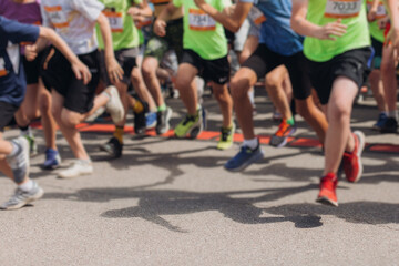 Marathon runners crowd, sportsmen participants start running the half-marathon in the city streets, crowd of sportswomen joggers in motion, group athletes outdoor training competition in a summer day
