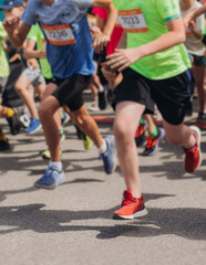 Marathon runners crowd, sportsmen participants start running the half-marathon in the city streets, crowd of sportswomen joggers in motion, group athletes outdoor training competition in a summer day