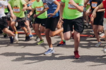Marathon runners crowd, sportsmen participants start running the half-marathon in the city streets, crowd of sportswomen joggers in motion, group athletes outdoor training competition in a summer day