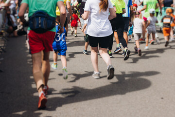 Marathon runners crowd, sportsmen participants start running the half-marathon in the city streets, crowd of sportswomen joggers in motion, group athletes outdoor training competition in a summer day