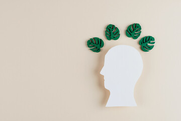 Human head shape with with green leaves on a light background. Concept of mental health and eco-anxiety. Responsible attitude towards the environment, personal actions to save the planet top view.