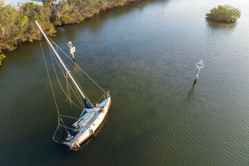 Half sunken sailing yacht capsized on shallow bay waters after hurricane Ian in Manasota, Florida