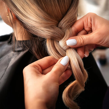 Close up nas m&atilde;os de uma cabeleireira fazendo um penteado nos cabelos de uma cliente.