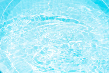 Blue water with ripples on the surface. Defocus blurred transparent blue colored clear calm water surface texture with splashes and bubbles. Water waves with shining pattern texture background.
