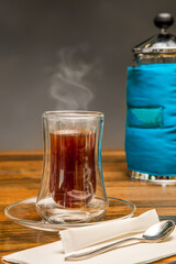 Hot Black tea served in steaming cup with French Press in the Background isolated on wooden table side view of hot drink