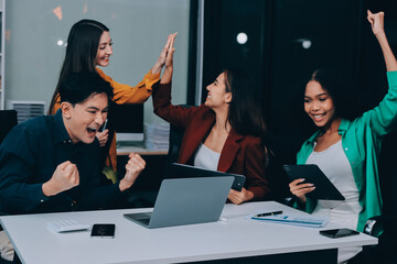 Young corporate employees sitting in office looking at laptop screen reading good news excited happy team diverse people celebrating victory win command success excellent result professional teamwork