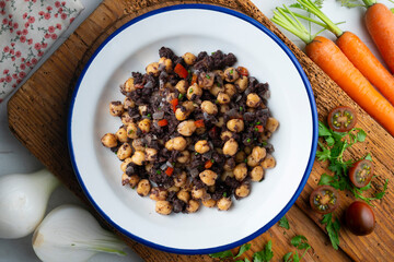 Sautéed chickpeas with black pudding and vegetables. Top view table with  decoration.
