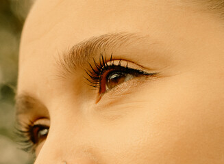 Close-up of eye with long lashes in warm lighting