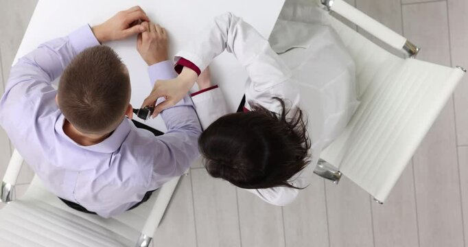 Female doctor checks ear of male patients with otoscope in medical office