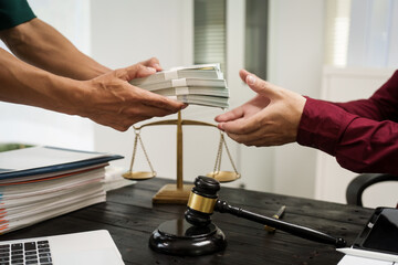 A male lawyer works at his desk, receiving cash from a client while considering the case. He focuses on law, justice, fairness, and the observance of legal rules and conventions in the system