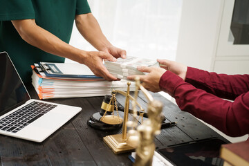 A male lawyer works at his desk, receiving cash from a client while considering the case. He focuses on law, justice, fairness, and the observance of legal rules and conventions in the system