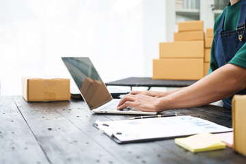 A man is working at his desk, preparing parcel boxes for shipment. He checks and packs items carefully, using shockproof materials, and attaches labels before sending them to customers via EMS.