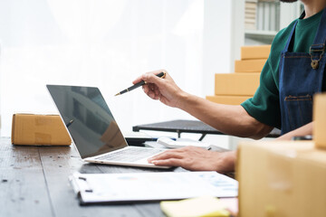 A man is working at his desk, preparing parcel boxes for shipment. He checks and packs items carefully, using shockproof materials, and attaches labels before sending them to customers via EMS.