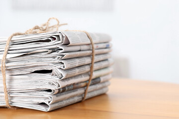 Stack of many newspapers on wooden table, space for text