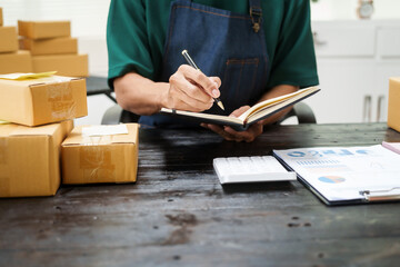 A man is working at his desk, preparing parcel boxes for shipment. He checks and packs items carefully, using shockproof materials, and attaches labels before sending them to customers via EMS.