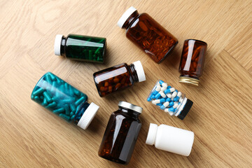 Pharmacist. Different pills in plastic bottles on wooden table, flat lay