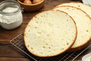 Tasty cut sponge cake and ingredients on wooden table, closeup