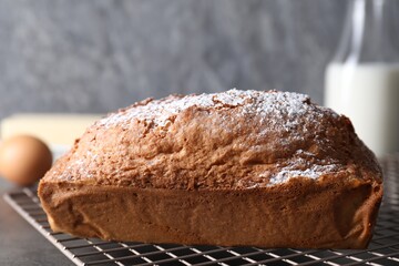 Tasty sponge cake with powdered sugar on grey table, closeup