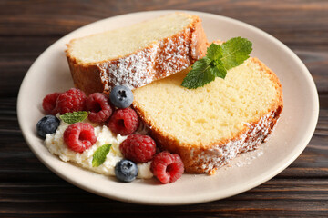 Freshly baked sponge cake, whipped cream, berries and mint on wooden table, closeup