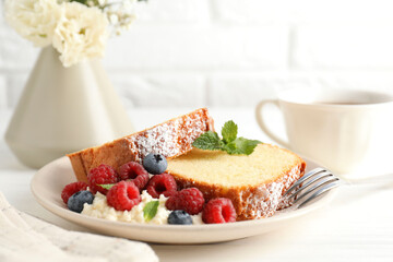 Freshly baked sponge cake, whipped cream, berries and mint on white wooden table, closeup