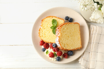 Freshly baked sponge cake, whipped cream, berries and mint on white wooden table, top view