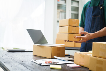 A man is working at his desk, preparing parcel boxes for shipment. He checks and packs items carefully, using shockproof materials, and attaches labels before sending them to customers via EMS.