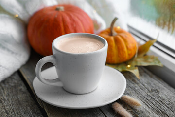 Cup of coffee and autumn decor on window sill, closeup