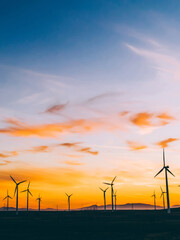 Silhouette of windmills station with propellers generating alternative clean green power from eco...